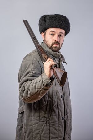 Peasant with a rifle on his shoulder, old-fashioned clothes, retro theme, studio shotの写真素材
