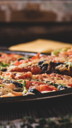 Fragrant pizza fresh from the oven, on the old wooden table. Vertical banner, matte effect techniqueの写真素材