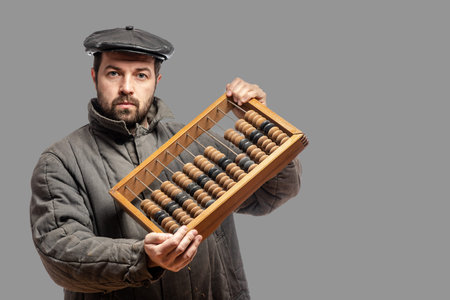 Old fashioned bearded man with wooden retro abacus, studio shot. Isolated on gray background, with...