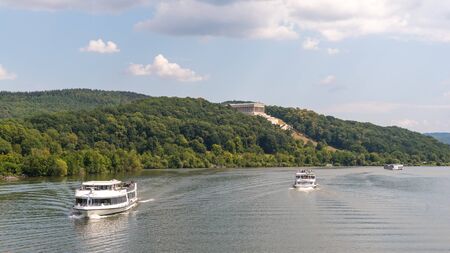 Donaustauf, Bavaria, Germany - July 27, 2018 : Ships with tourists sails on Danube River, Walhalla memorial on the hill, tour tourism, banner 16x9のeditorial素材