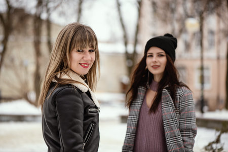 Two young trendy women in snowy winter park.