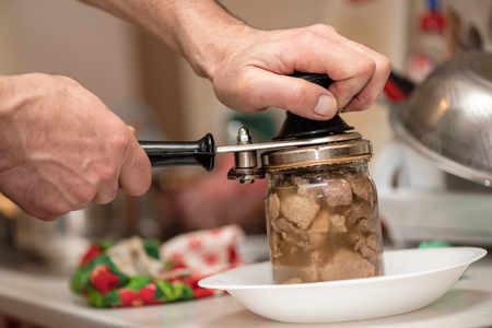 Man is canning pork stew, process close-up. Homemade cooking with a traditional recipe, Ukrainian cuisine.の写真素材