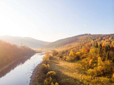 Colorful autumn. Aerial drone view of scenic natural landscape, river, mountains and forests, slopes and valley.の写真素材