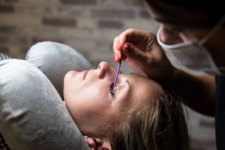 Application of glue on eyelashes, fixing. Cosmetic procedure in beauty salon. Process of eyelash extension. Beauty and self-careの写真素材