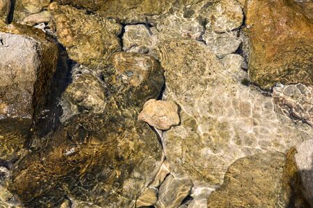 Stones in clear water, sun reflection, summer. Natural background, top view, close up.の写真素材