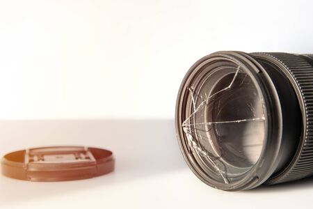 Crushed filter and saved lens of a digital camera, sample with copy space for text on background. Broken glass of UV filter near the on table. Concept - save your lensの写真素材
