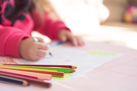 Color pencils lying on the table. Process of drawing by a little child, close up view. Soft background with copy space. Themes of child development, leisure and hobby.の写真素材