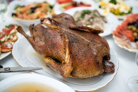 Freshly baked duck on the plate with other dishes on a holiday tableの写真素材