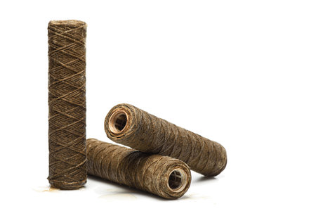 Set of used rope water filters on white with copy space. Clogged and dirty string water filters,...