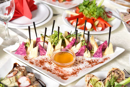 Set of cheese decorated with herbs and honey. Banquet table with delicious food in a restaurant. Professional and exquisite dish serving at restaurant. Catering service.の写真素材