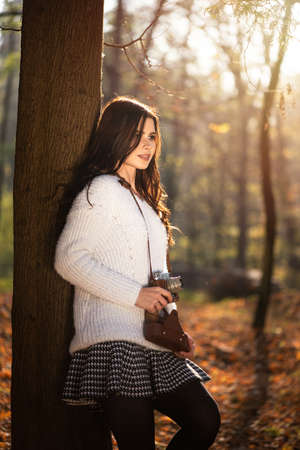 Beautiful woman with retro camera. In the autumn park. Enjoying your favorite thing.の写真素材