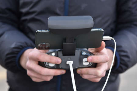 10 April 2022 - Krakow, Poland: Pilot holds the remote controller of Drone Parrot ANAFI Thermal in hends and remotely controls the drone.のeditorial素材
