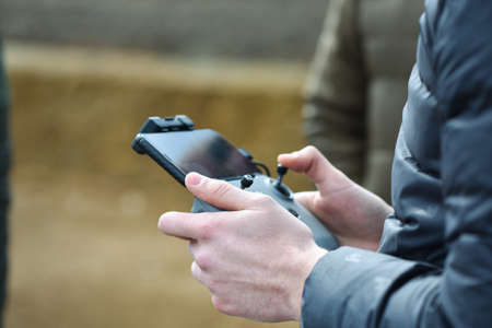 10 April 2022 - Krakow, Poland: Pilot holds the remote controller of Drone DJI in hands and remotely controls drone.のeditorial素材