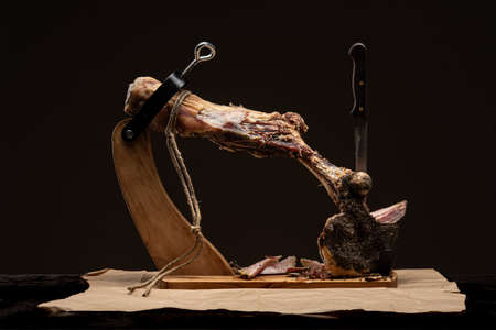 Jamon on a wooden stand for cutting meat. Piece of jamon on jamonero. Ham, jamon, prosciutto. Studio shot.の写真素材
