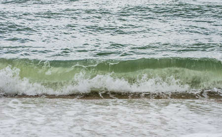 Green sea waves continuously washed ashoreの写真素材