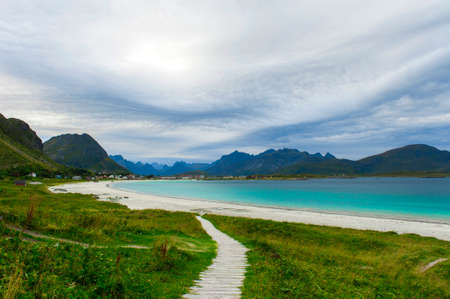 Rambergstranda beach on the Lofoten islands in cloudy weather. Mountains, sandy beach, grass and azure water. Norway sea.の写真素材
