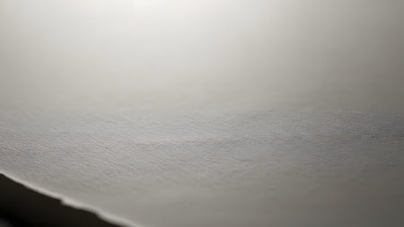 Minimalist close-up of a light grey and white textured surface, possibly paper or fabric, with subtle tonal variations and a distinct torn edge. Abstract background with copy space.の素材