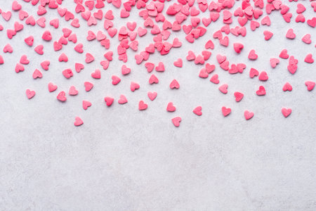 Valentine's Day light background with pink candy hearts falling from above.