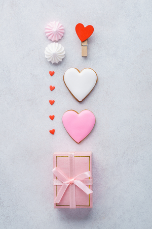 Valentine's Day preparation concept. Gift box with pink ribbon, heart shaped cookies, meringues and candy. Flat lay.の写真素材