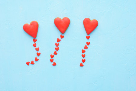 Red heart shaped balloons made of cookies and candy fly out. Valentine's Day and love concept. Blue...