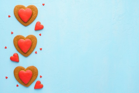 Red heart shaped cookies on pastel blue background. Creative layout design for Valentine's Day.の写真素材