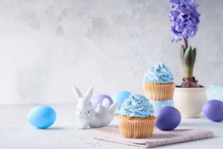Easter vanilla cupcakes, colored eggs, cute bunny and hyacinth in a flower pot. Holiday concept with copy space.の写真素材