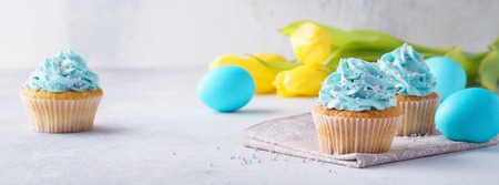 Easter vanilla cupcakes with cream cheese frosting, eggs and tulips. Happy Easter banner.の写真素材