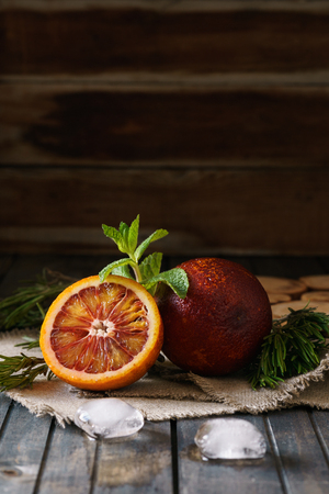 Sliced and whole ripe juicy blood oranges and ice on wooden background.の写真素材