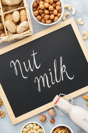 Nut milk and ingredients. Milk alternatives. Chalkboard lettering. Almond, walnut, hazelnut, pecan and brazil nutの写真素材