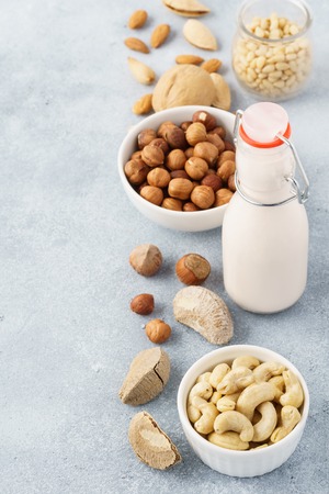 Dairy free nut milk in a glass bottle and various raw nuts. Health and dieting.の写真素材