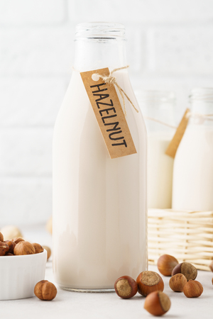 Hazelnut milk in a bottle with tag and raw ingredients. Light background.の写真素材