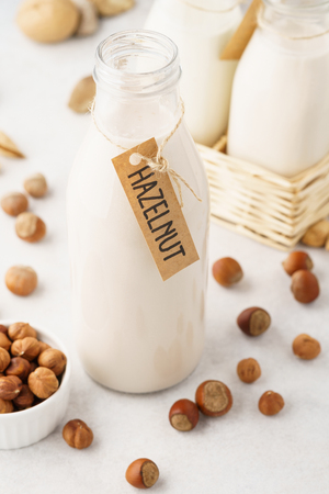 Hazelnut milk in a bottle with tag and raw ingredients. Light background.の写真素材