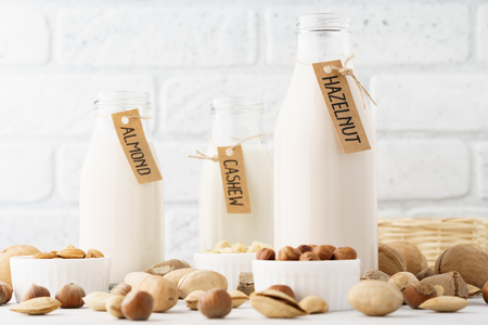 Set of various nut milk in bottles - almond, cashew, hazelnut and raw ingredients.の写真素材