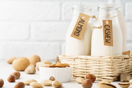 Different nut milk in bottles with tags - almond, cashew and ingredients. Dairy free, no lactose milk concept with copy space.の写真素材