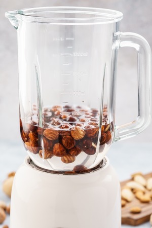 Blender and hazelnuts soaked in water. Making healthy vegan milk. Step by step recipe.の写真素材
