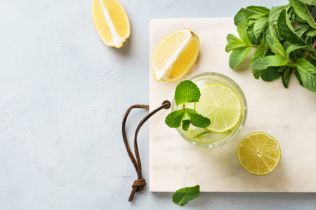 Cold lemonade with fresh lemon, lime and mint in a glass. Refreshing summer drink concept with...