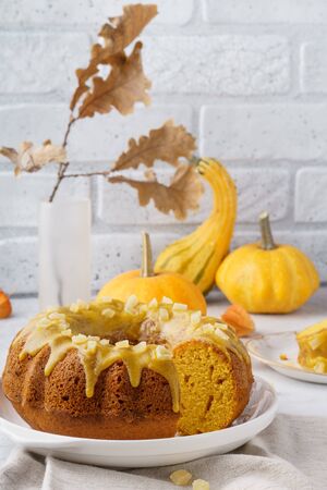 Pumpkin bundt cake topped with sugar glaze and candied fruits. Fall pastry concept with copy space.の写真素材
