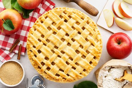 Homemade apple pie with lattice top and ingredients for cooking. Traditional American seasonal pastry concept.の写真素材