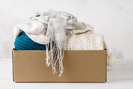 Winter clothes in a cardboard box. Seasonal clothing for shipping or donation.