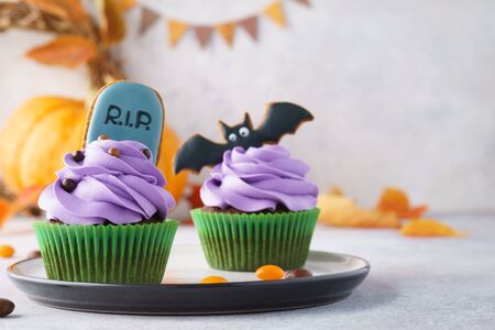 Halloween cupcakes decorated with homemade gingerbread cookies: tombstone and bat. Festive treats concept with copy space, selective focus.の写真素材