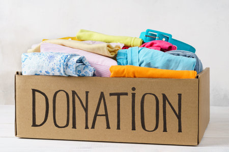 Donation box with various colorful clothes on a table.