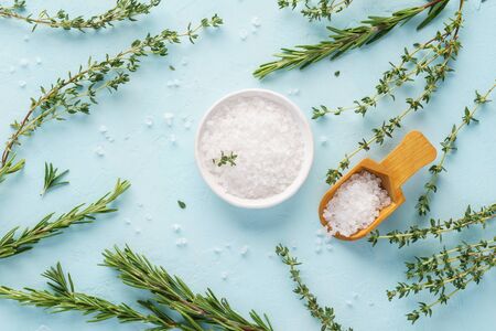 Coarse sea salt, fresh thyme and rosemary twigs on light blue background. Set of herbs and spices for cooking. Seasoning for vegetables, meat or poultry.の写真素材