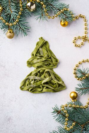 Christmas tree made of fresh homemade spinach pasta. Xmas background with fir-tree branches and decoration.の写真素材