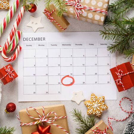 Planner page with Christmas gift boxes and decoration around. 25th of December marked with red circle on calendar. Xmas preparation concept.