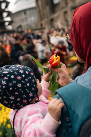 Child Reaches for a Tulip at a Public Flower Event in Berlin