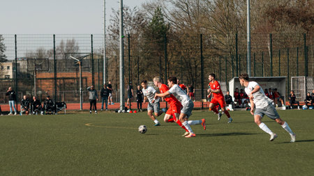 A football player from Berliner AK 07 controls the ball during a match against Anker Wismar on March 7, 2026 in Wismar, Germany. The scene captures active play and teamwork on a sunny soccer pitch.