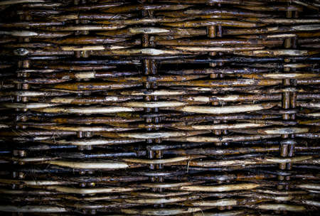 Old wicker fence of willow twigs. Abstract background.の写真素材
