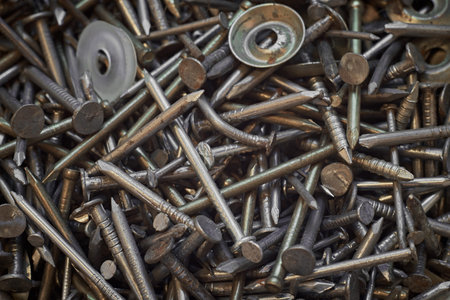 A bunch of different iron construction nails, close-up. Abstract background.