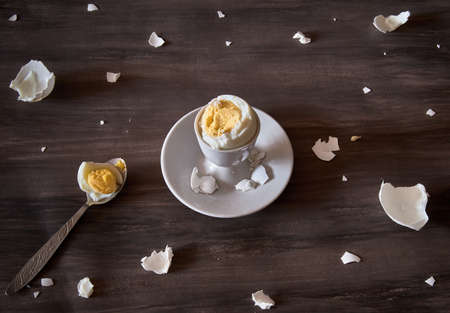 Breakfast still life. Boiled soft-boiled egg on a stand with a spoon, with pieces of eggshell. The view from the top.の写真素材