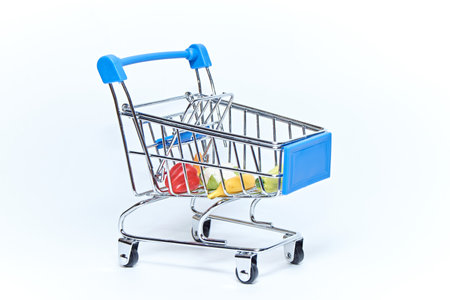 Blue mini grocery cart from supermarket with groceries on white background. Consumer concept.の写真素材
